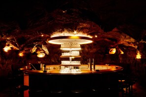 A bar with a central chandelier, surrounded by stools and a bar counter. - Hotel Silvretta (Kappl)