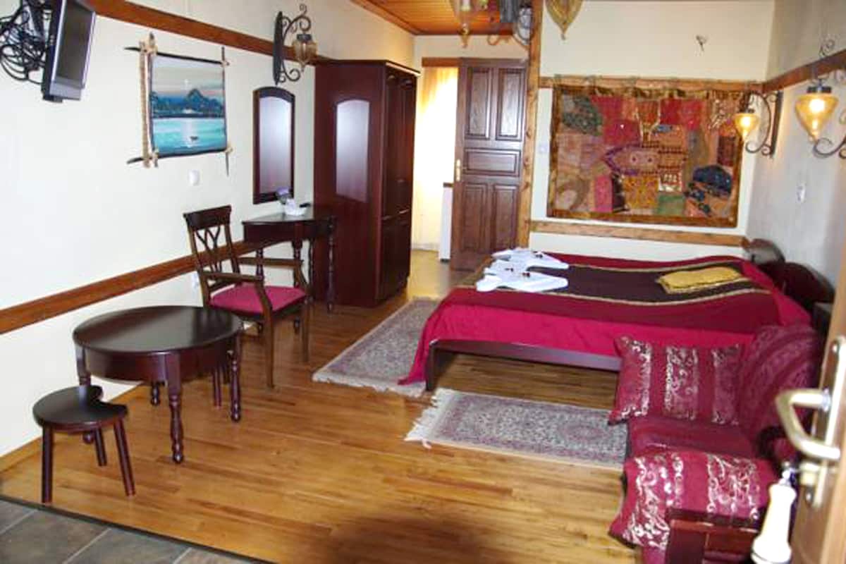A room with a bed, a desk, and a chair. There is a window with a view of the outside.