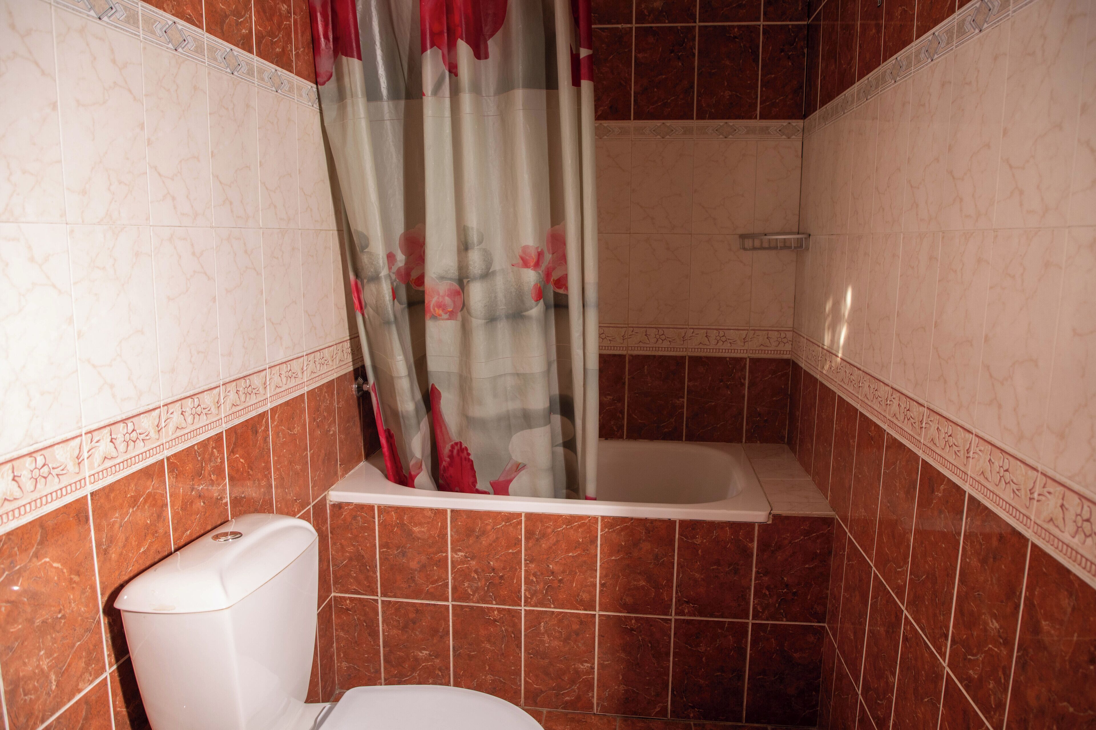 A bathroom with a bathtub, toilet, and shower curtain.