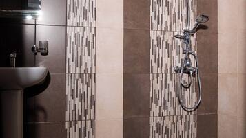 A modern bathroom with a shower, a sink, and a patterned tile wall.