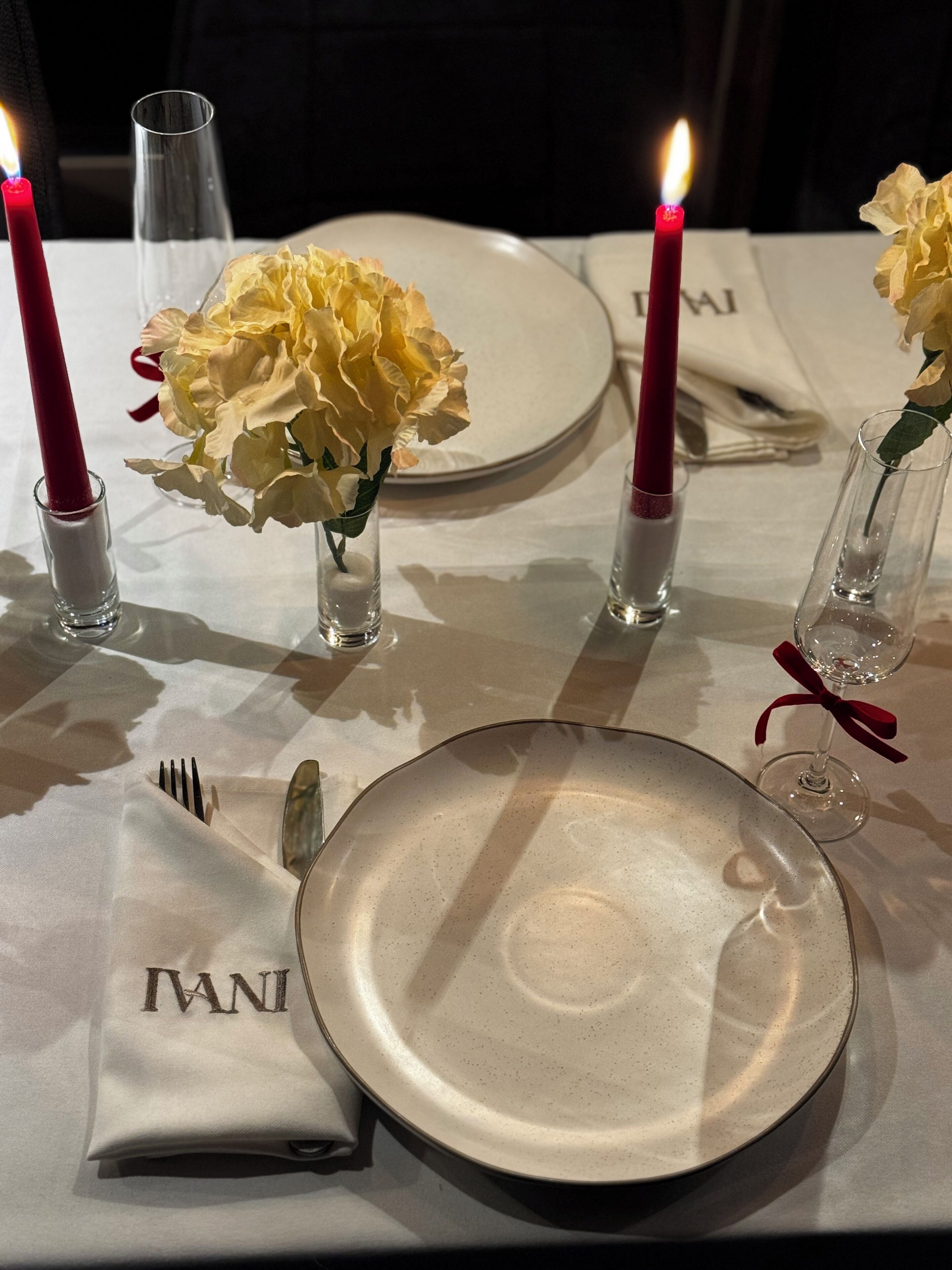 Una mesa dispuesta con un plato, cubiertos, servilleta y velas.