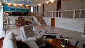 Un amplio salón con escaleras, comedor y vistas al mar a través de grandes ventanales.