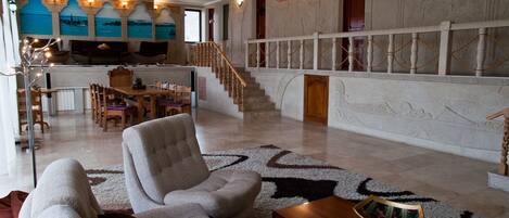 Un amplio salón con escaleras, comedor y vistas al mar a través de grandes ventanales.