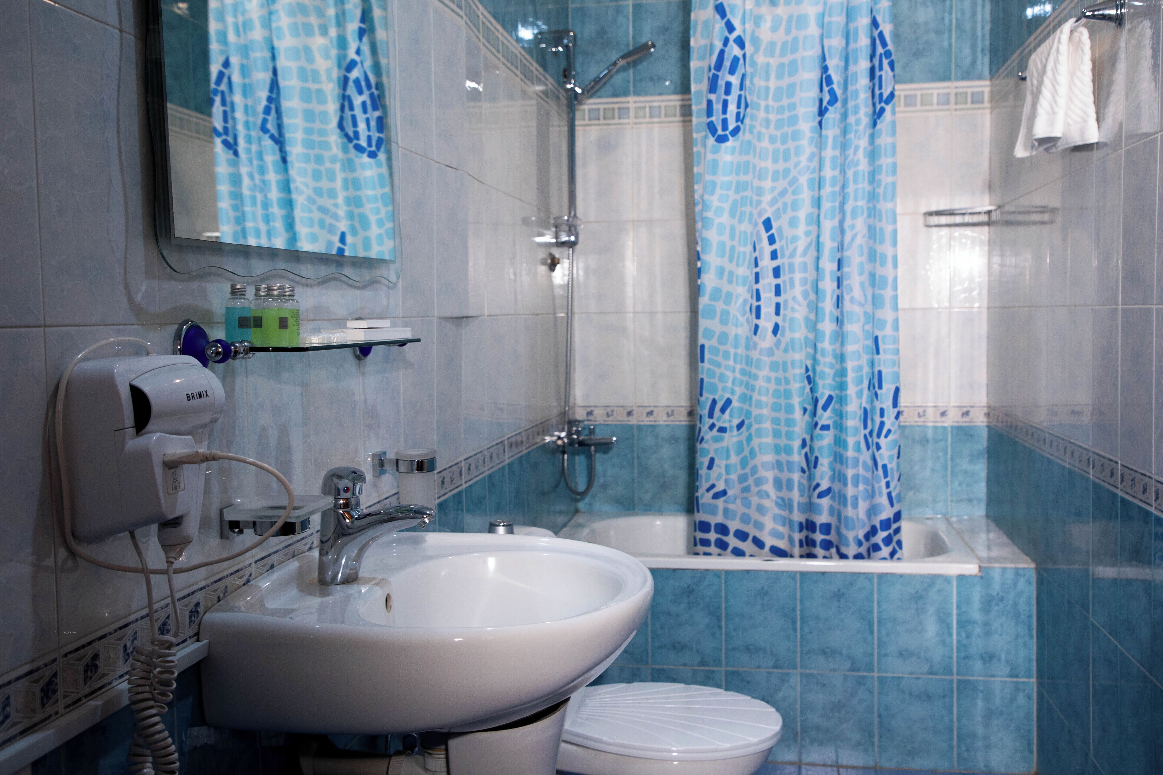 A bathroom with a sink, toilet, shower, and a mirror.