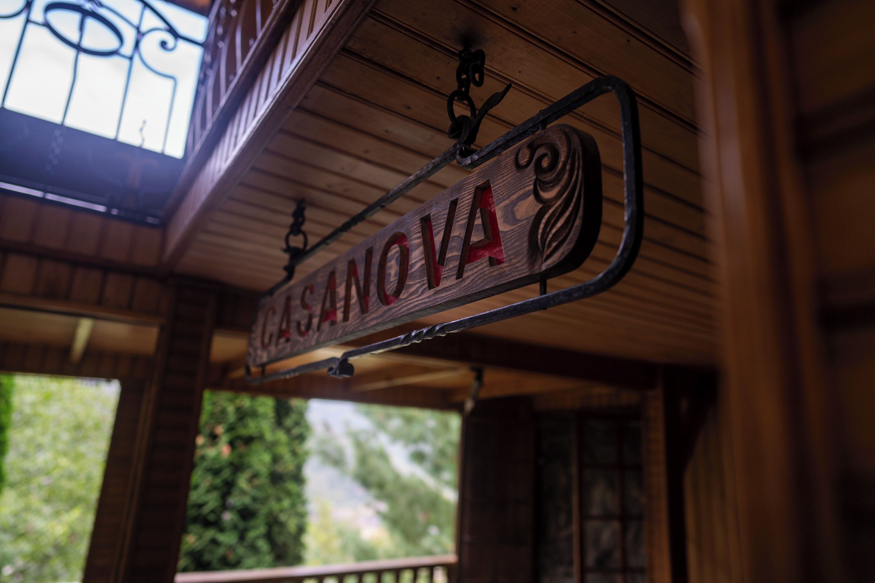 A wooden sign with the name "CASANOVA" hanging from a balcony.