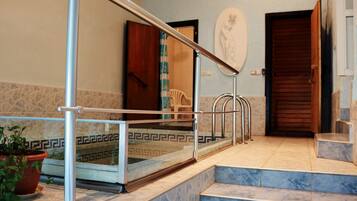 Una escalera con barandillas de metal, una planta en maceta y un piso con diseño que conduce a una puerta.