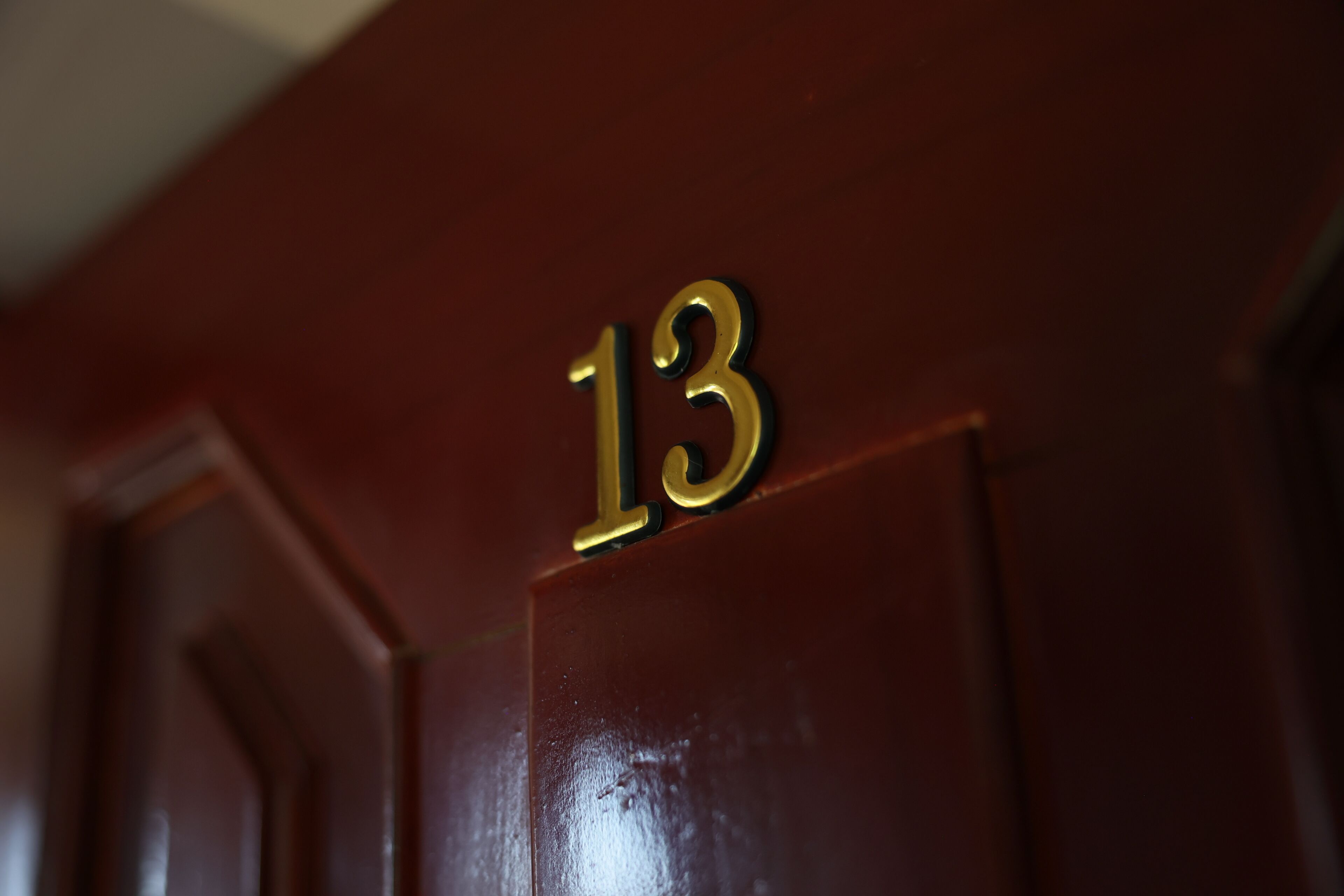 A close-up of a wooden door with a brass number '13' sign.
