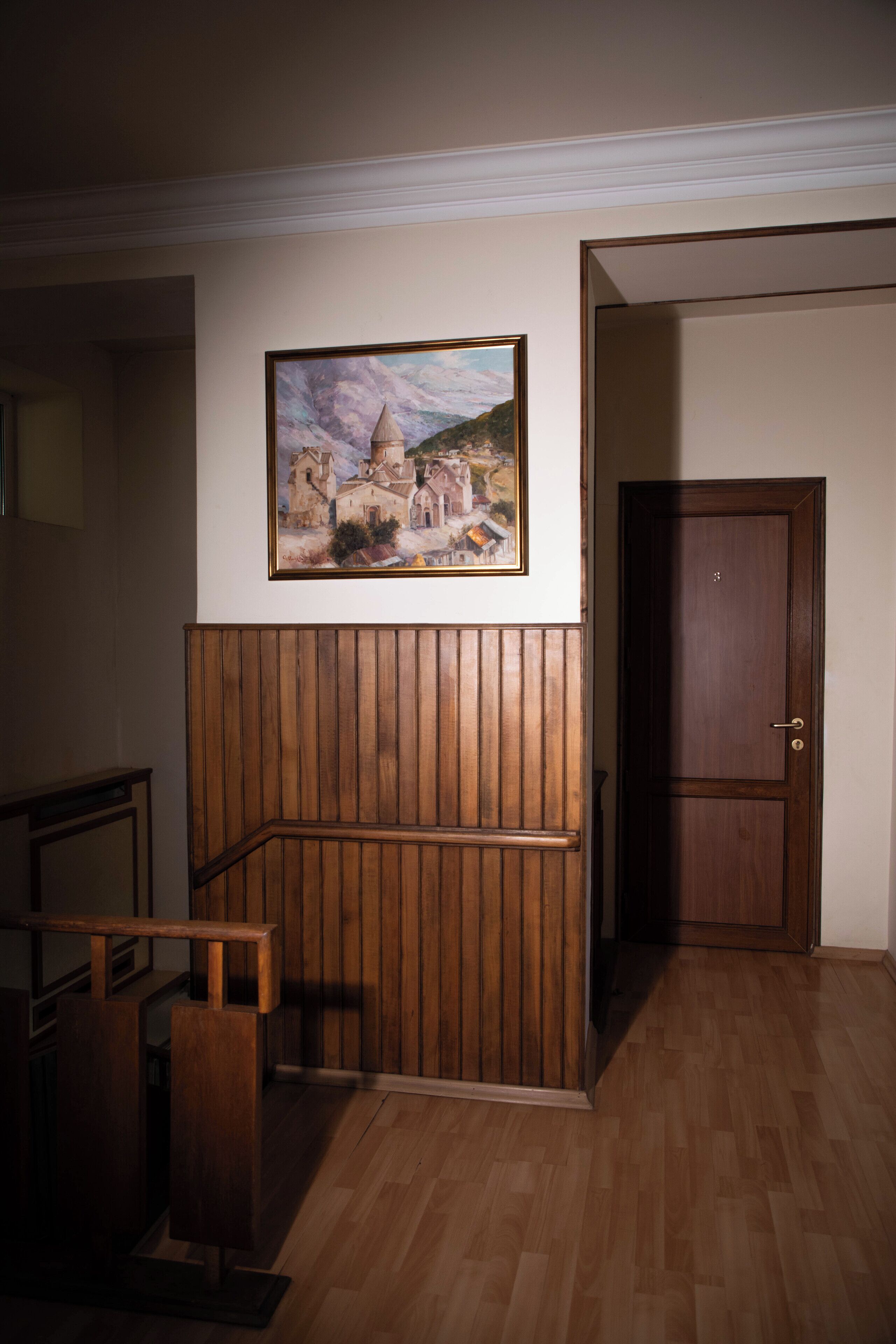 Una habitación con un banco de madera, una puerta y un cuadro enmarcado en la pared.