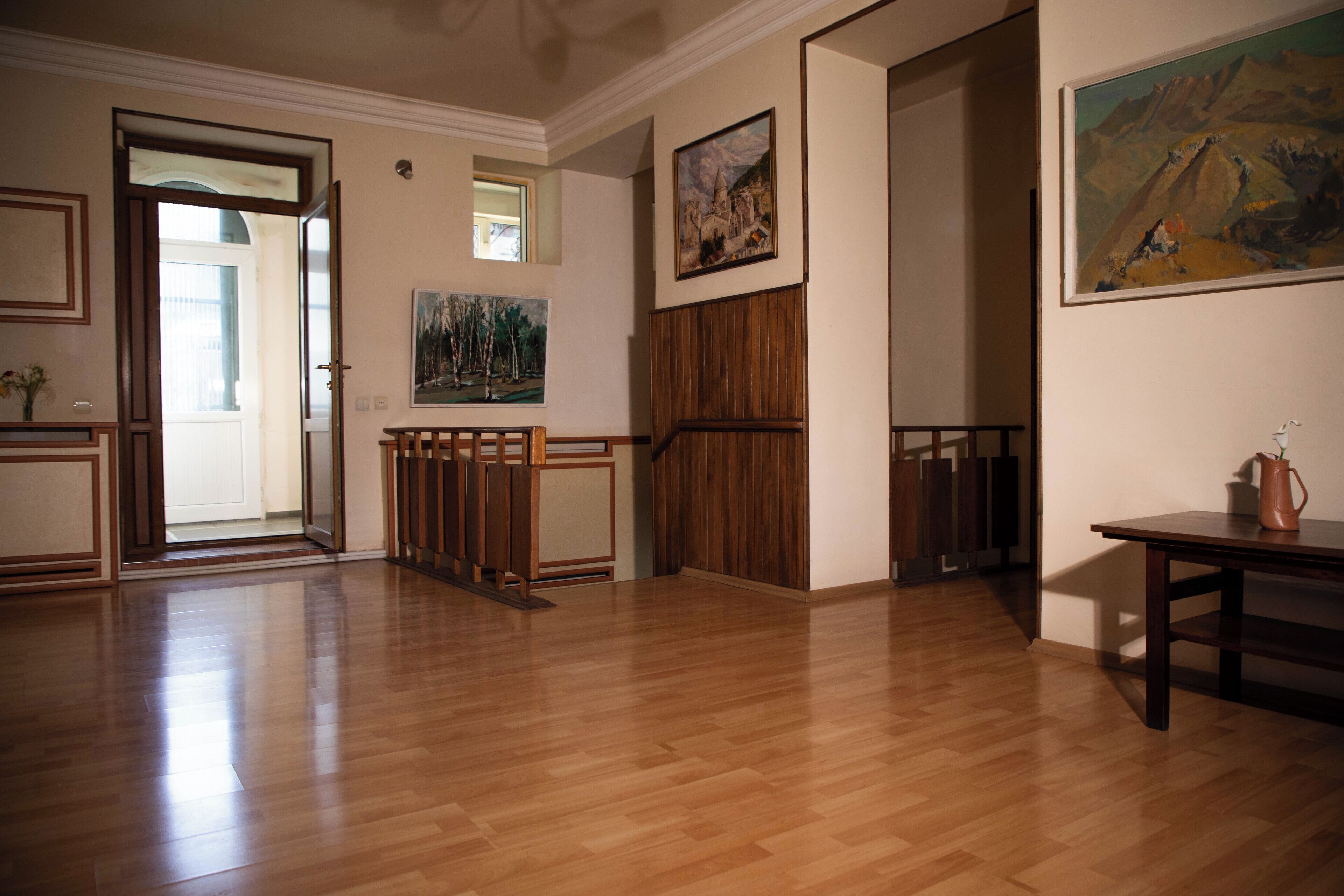 A spacious room with wooden flooring, a wooden staircase, and a painting on the wall.