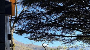 Una terraza de madera con dos sillas de metal, con vistas a un paisaje montañoso.