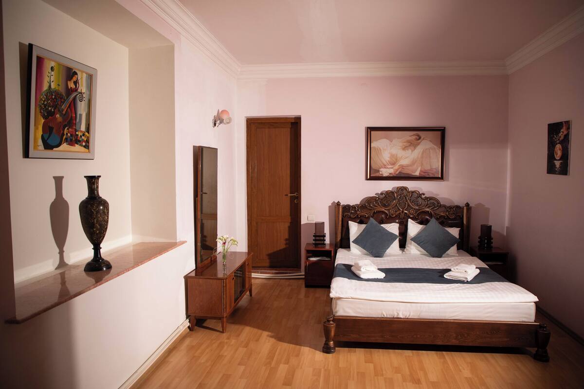 A bedroom with a wooden bed, a nightstand, a dresser, and a door.