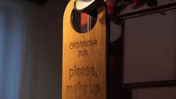 A hand holding a key, inserting it into a door with a wooden sign that reads "CASANOVA INN please, make up my room."