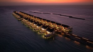 A row of overwater bungalows connected by a walkway, with a sunset in the background. - OBLU NATURE Helengeli - All-Inclusive with Free Transfers (Helengeli)