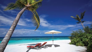 A beach with white sand, a palm tree, a red lounge chair, and a white umbrella. - OBLU NATURE Helengeli - All-Inclusive with Free Transfers (Helengeli)