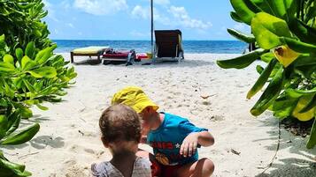 Am Strand, weißer Sandstrand, Liegestühle, Sonnenschirme