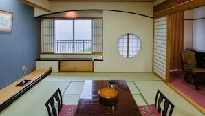 Een traditionele Japanse kamer met tatami vloeren, een houten tafel met een theeset, een shoji scherm en uitzicht door een raam met een balkon.