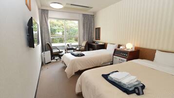 A hotel room with two beds, a desk, a chair, a TV, and a window with curtains.