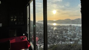 Een kamer met een groot raam met uitzicht op een stadsgezicht tijdens de zonsondergang.