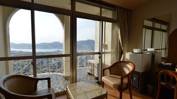 A balcony with a view of a cityscape and mountains, furnished with a table and chairs.