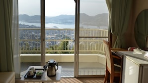 Een kamer met een balkon met uitzicht op een stadslandschap en water.