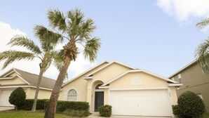 A residential house with a beige exterior, a dark front door, and a garage. - Glenbrook Homes (Clermont)