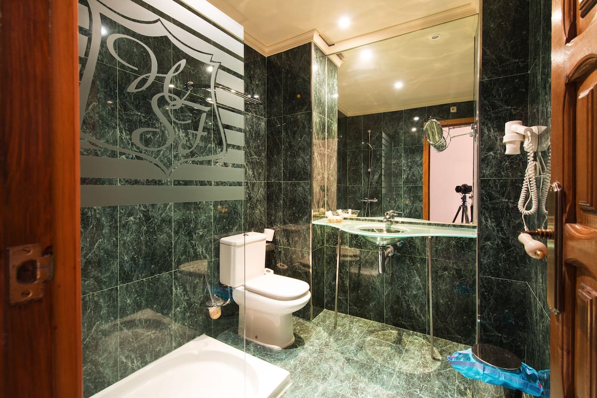 Een moderne badkamer met een glazen wastafel, toilet en douche.