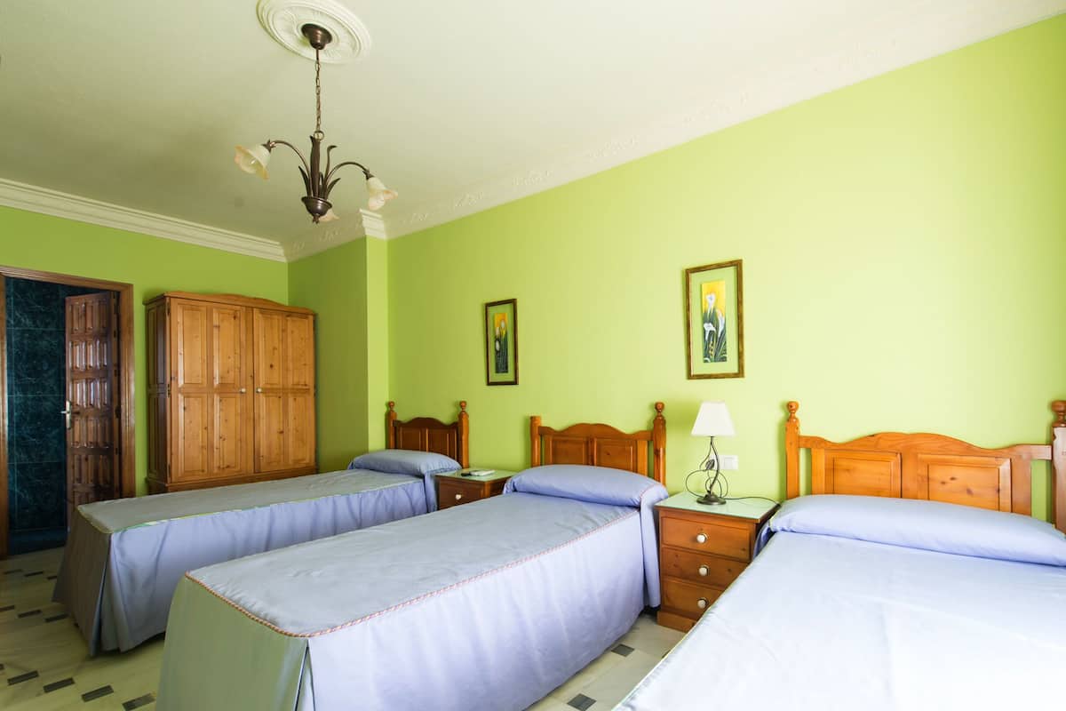 Een kamer met twee eenpersoonsbedden, een houten garderobe, een nachtkastje met een lamp en een deur naar een badkamer.