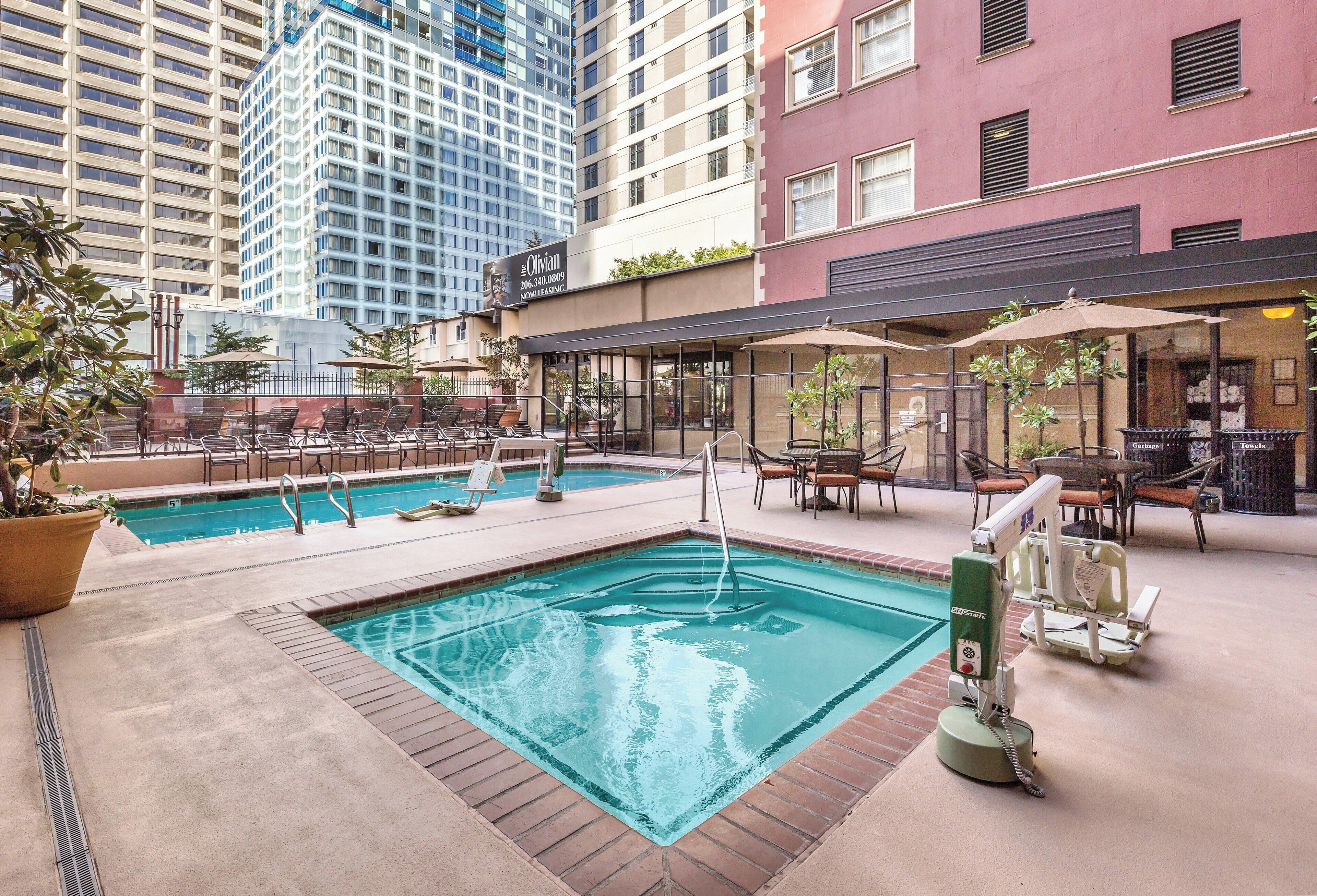 A hotel pool area with two pools, outdoor seating, and a lifeguard stand.