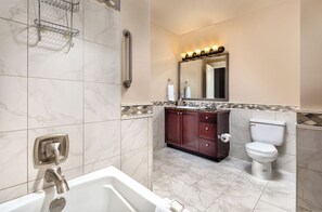 A modern bathroom with a bathtub, a toilet, and a vanity with a mirror. - WorldMark Seattle - The Camlin (Seattle)