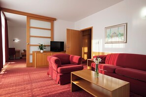 A living room with a red sofa set, a wooden coffee table, a TV on a wooden stand, and a painting on the wall. - Izvir (Radenci)