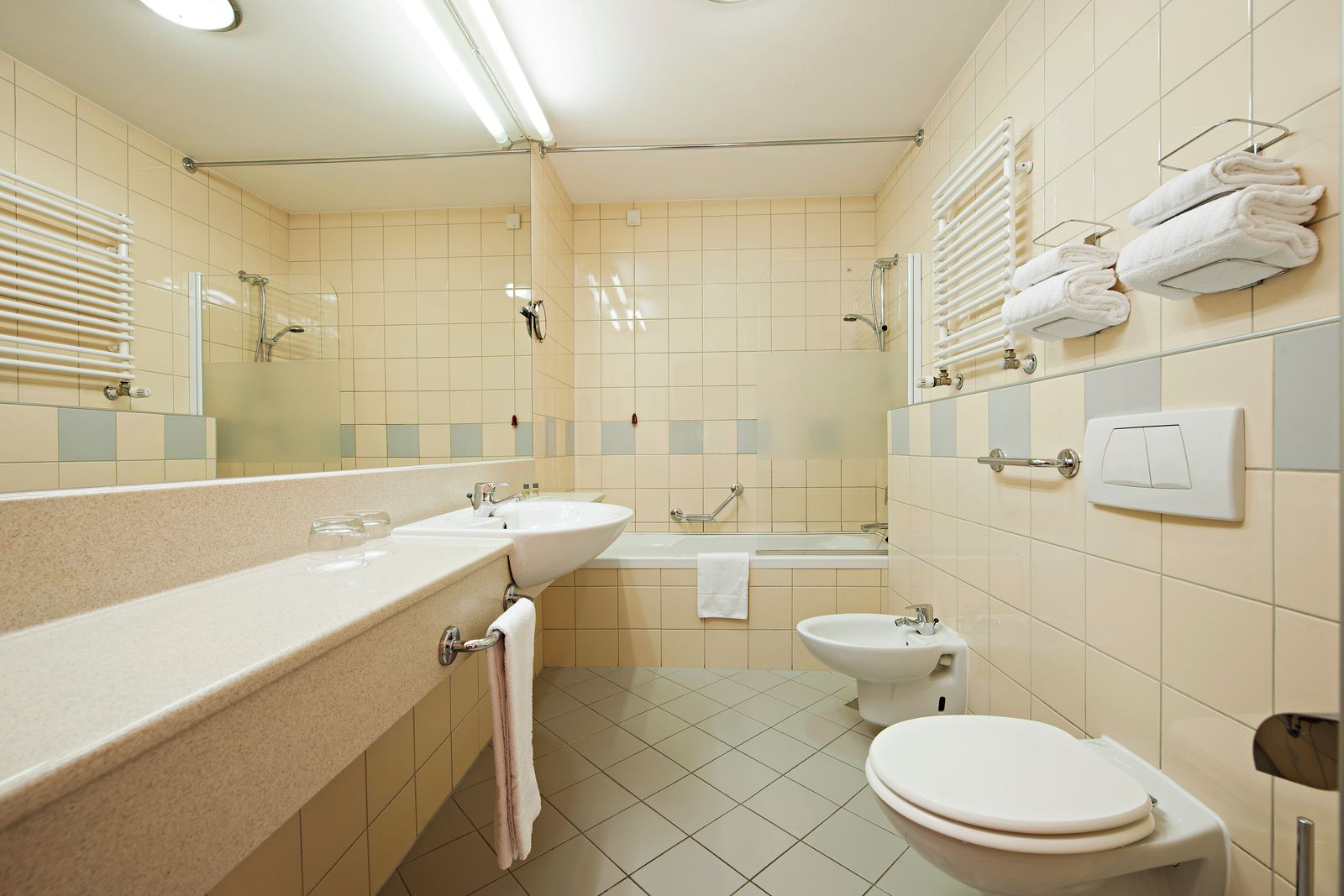 Ein Badezimmer mit Waschbecken, Spiegel, Handtuchhalter, Toilette und Badewanne.