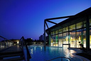 An indoor swimming pool with a glass enclosure, a wooden deck, and a metal structure. - Izvir (Radenci)