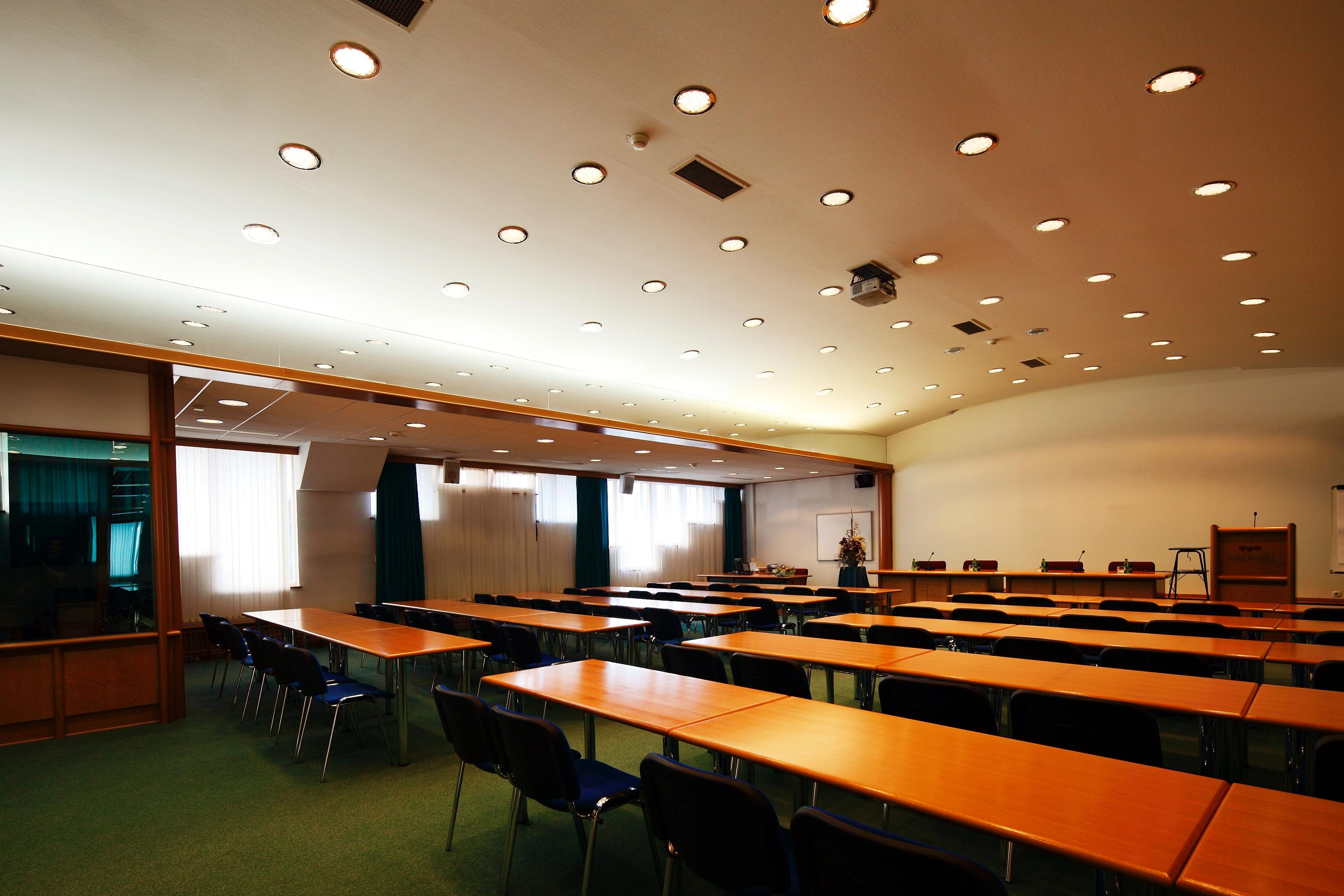 A conference room with multiple tables and chairs, a whiteboard, and a projector.