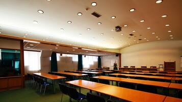 A conference room with multiple tables and chairs, a whiteboard, and a projector.