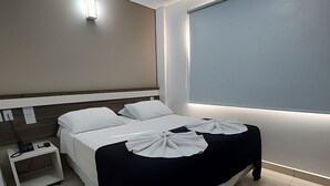 A modern hotel room with a large bed, a bedside table, and a window with a view. - San Lucas Hotel (Sarandi)