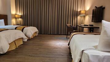 Een hotelkamer met twee bedden, een bureau, een stoel en een televisie.