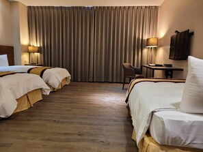 A hotel room with two beds, a desk, a chair, and a TV. - Sankaikan Hotel (Puzi)