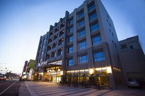 A multi-story hotel with a ground-level restaurant and outdoor seating. - Sankaikan Hotel (Puzi)