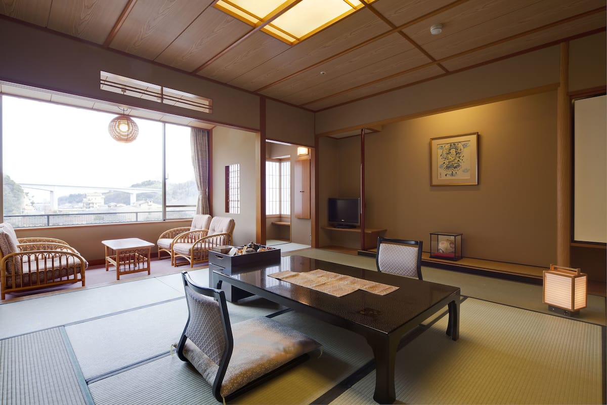 Une pièce de style japonais traditionnel, avec un sol recouvert de tatamis, une table basse avec des coussins et un téléviseur.