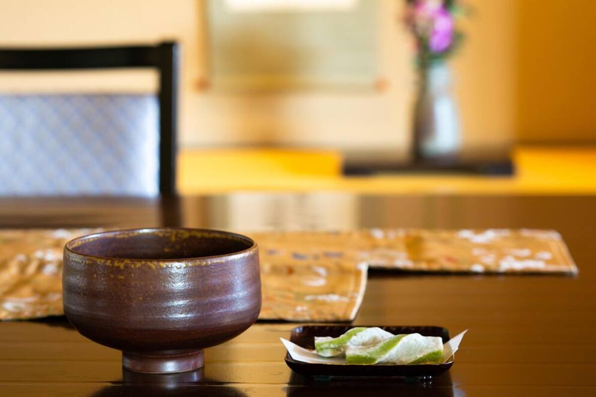 Une table en bois sur laquelle se trouvent un bol en céramique et une petite assiette de nourriture.