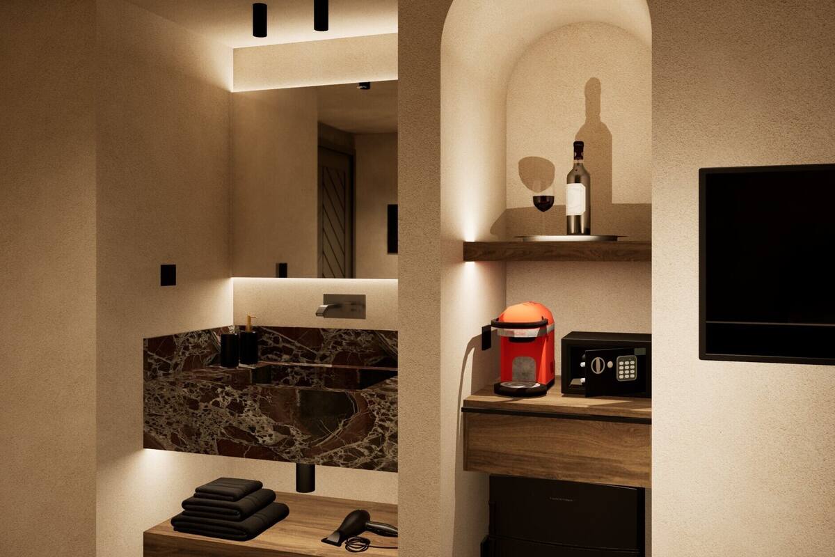 A modern bathroom with a marble sink, a coffee machine, a hairdryer, and a TV mounted on the wall.