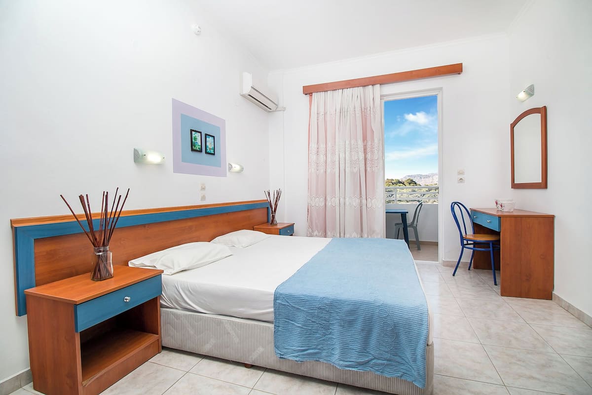 A bedroom with a bed, bedside tables, a desk, and a chair.