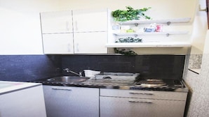 A compact kitchen with a sink, stove, and cabinets. - Studio Orient (Belgrade)