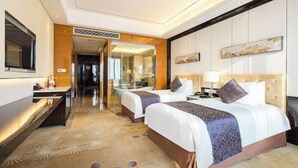 A hotel room with two beds, a desk, a TV, and a bathroom visible through an open door. - New Century Grand Hotel Siyang (Suqian)
