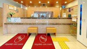 A hotel reception area with a marble counter, two wooden benches, a reception desk, and a sign that reads "FRONT". - Toyoko Inn Yokohama Shinkoyasu Ekimae (Yokohama)