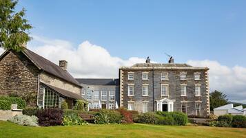 A large stone building with multiple windows and a well-maintained lawn.
