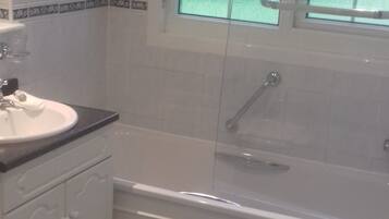 Une salle de bain avec un lavabo blanc, une baignoire et une douche.