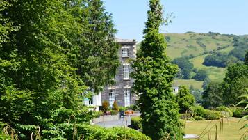 A stone building surrounded by lush greenery and hills.