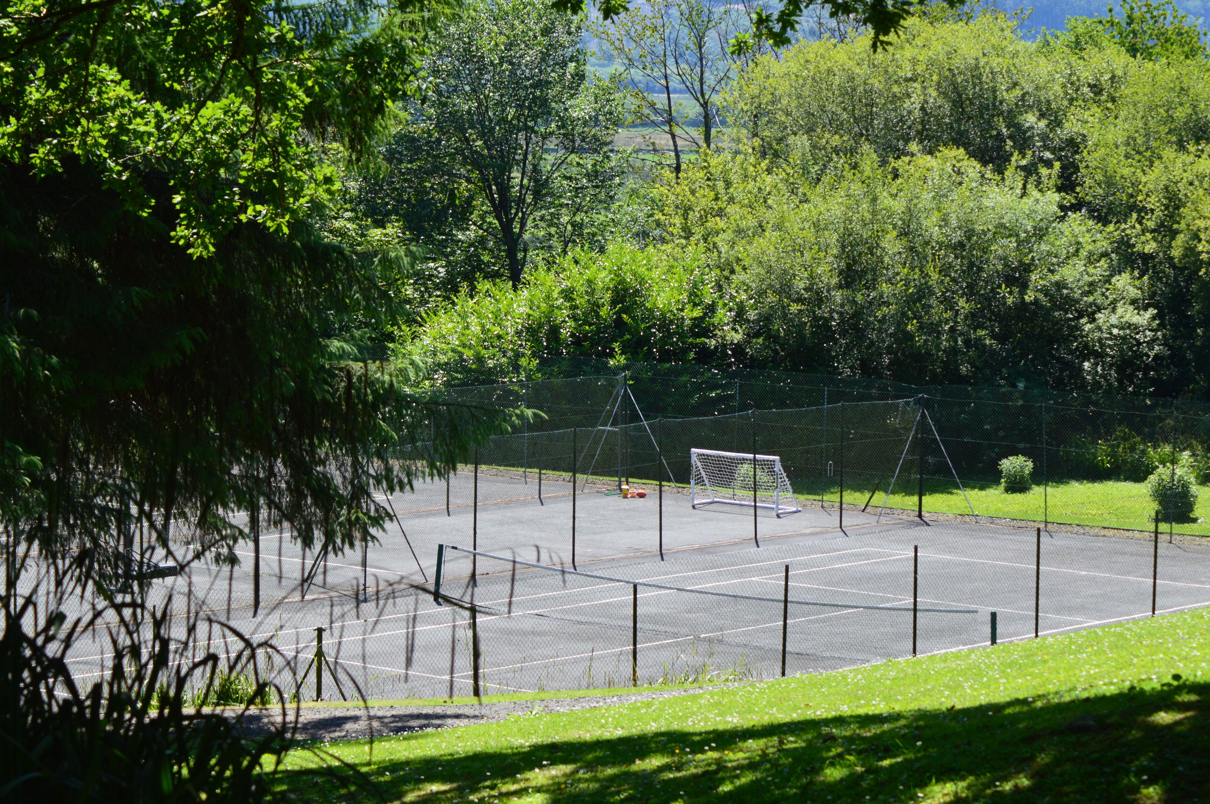 A tennis court surrounded by trees and a fence.