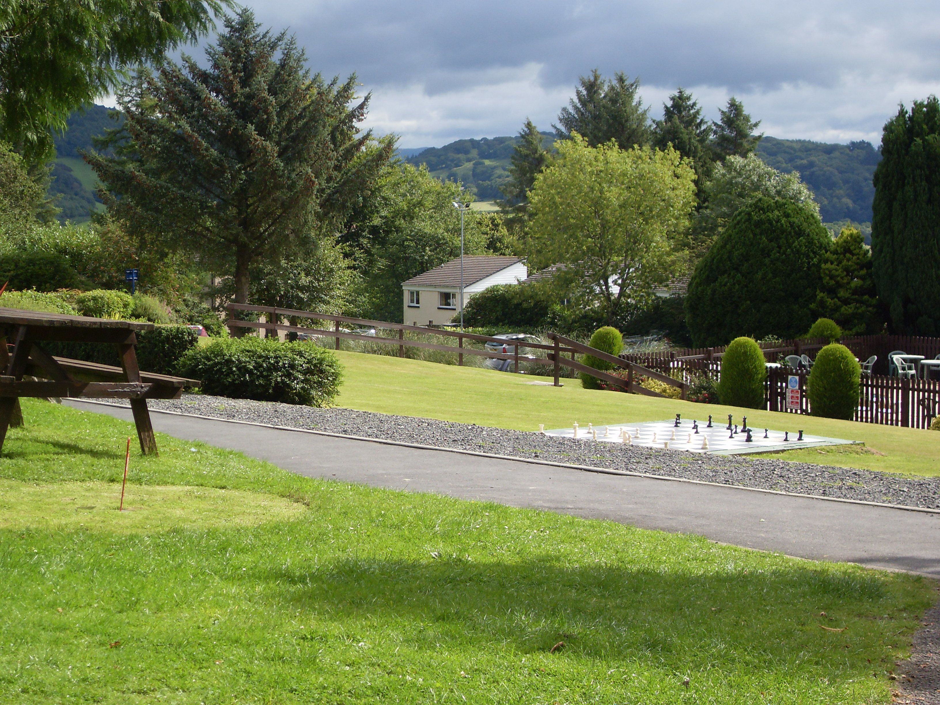 A park with a chessboard, picnic tables, and a walking path.